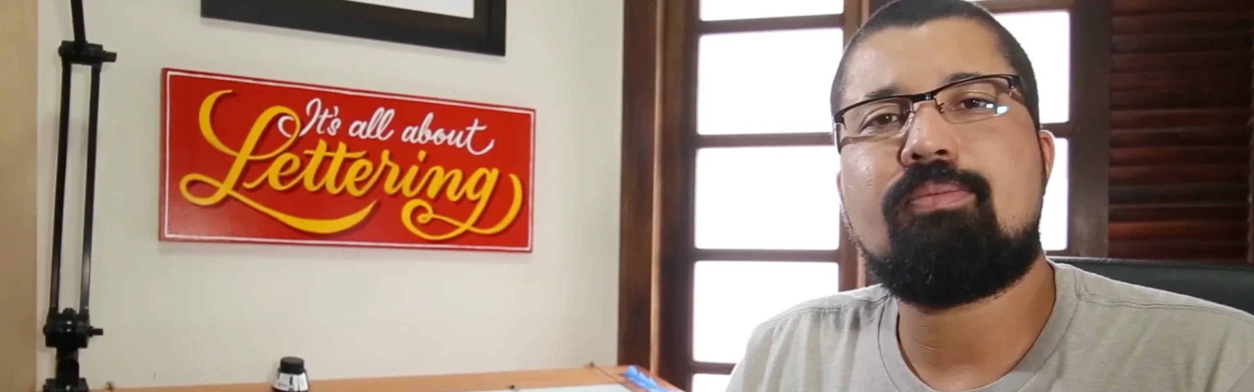 Jackson Alves in his studio, beneath a hand-painted sign reading It’s all about Lettering.